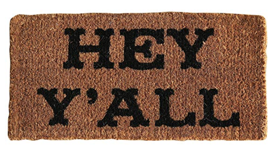A brown welcome mat with Hey Y'all written in black